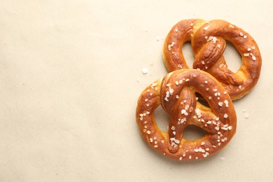 Photo of Tasty pretzels with salt on beige background, flat lay. Space for text