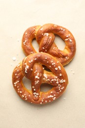 Photo of Tasty pretzels with salt on beige background, flat lay
