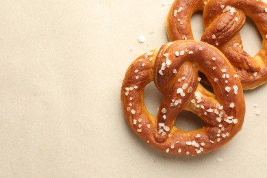 Photo of Tasty pretzels with salt on beige background, flat lay. Space for text
