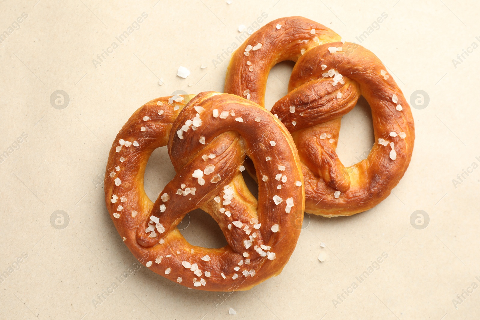 Tasty pretzels with salt on beige background, flat lay Photo of Tasty pretzels with salt on beige background, flat lay