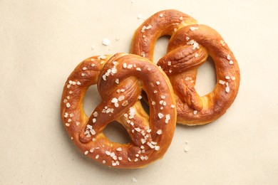 Photo of Tasty pretzels with salt on beige background, flat lay