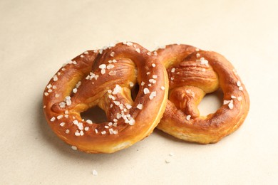 Photo of Tasty pretzels with salt on beige background, closeup