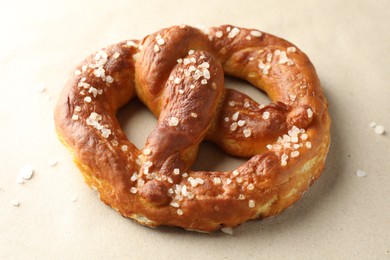 Photo of Tasty pretzels with salt on beige background, closeup