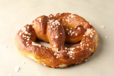 Photo of Tasty pretzels with salt on beige background, closeup