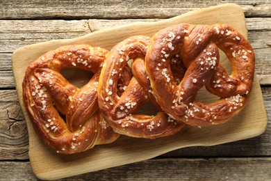 Photo of Tasty pretzels with salt on wooden table, top view