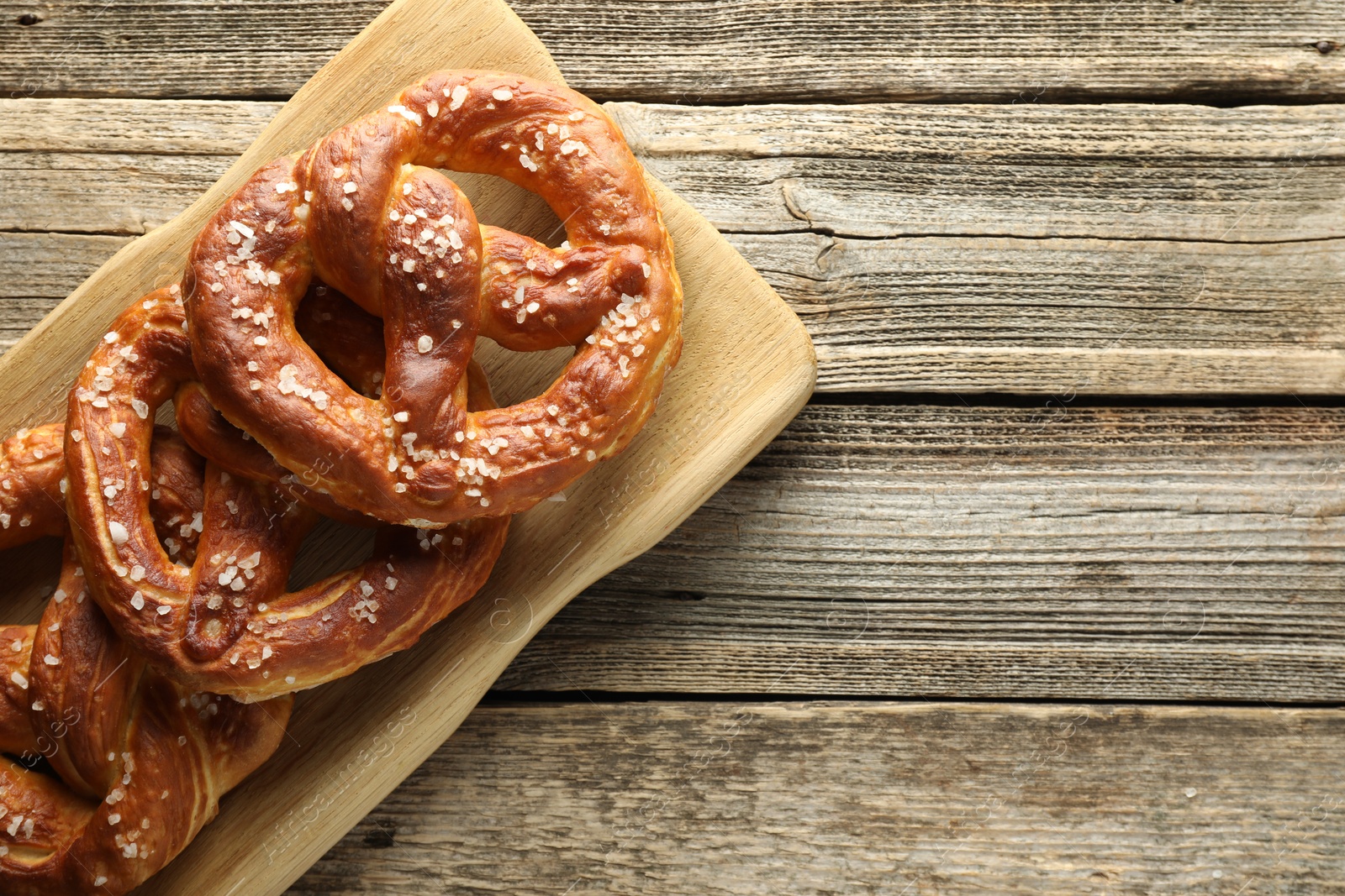 Tasty pretzels with salt on wooden table, top view. Space for text Photo of Tasty pretzels with salt on wooden table, top view. Space for text