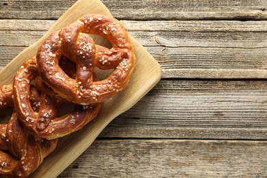 Photo of Tasty pretzels with salt on wooden table, top view. Space for text