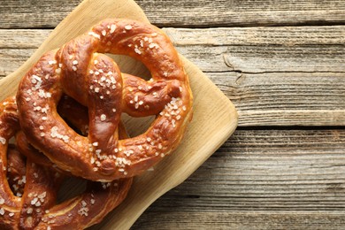 Photo of Tasty pretzels with salt on wooden table, top view. Space for text