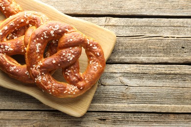 Photo of Tasty pretzels with salt on wooden table, top view. Space for text