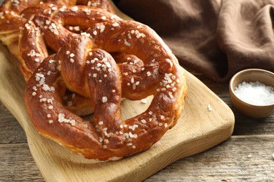 Photo of Tasty pretzels with salt on wooden table, closeup