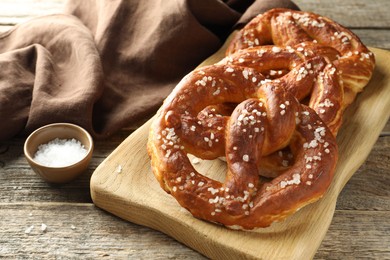 Photo of Tasty pretzels with salt on wooden table, closeup
