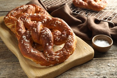 Photo of Tasty pretzels with salt on wooden table, closeup