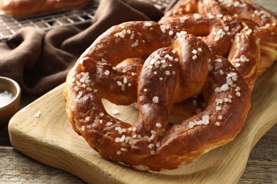 Photo of Tasty pretzels with salt on wooden table, closeup