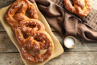 Photo of Tasty pretzels with salt on wooden table, flat lay