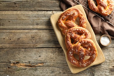 Photo of Tasty pretzels with salt on wooden table, flat lay. Space for text