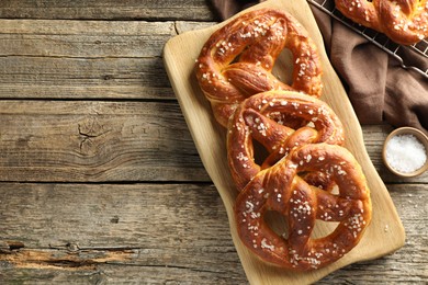 Photo of Tasty pretzels with salt on wooden table, flat lay. Space for text