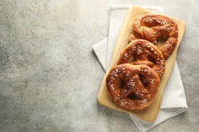 Photo of Tasty pretzels with salt on grey table, top view. Space for text