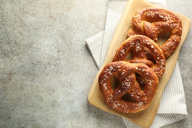 Photo of Tasty pretzels with salt on grey table, top view. Space for text