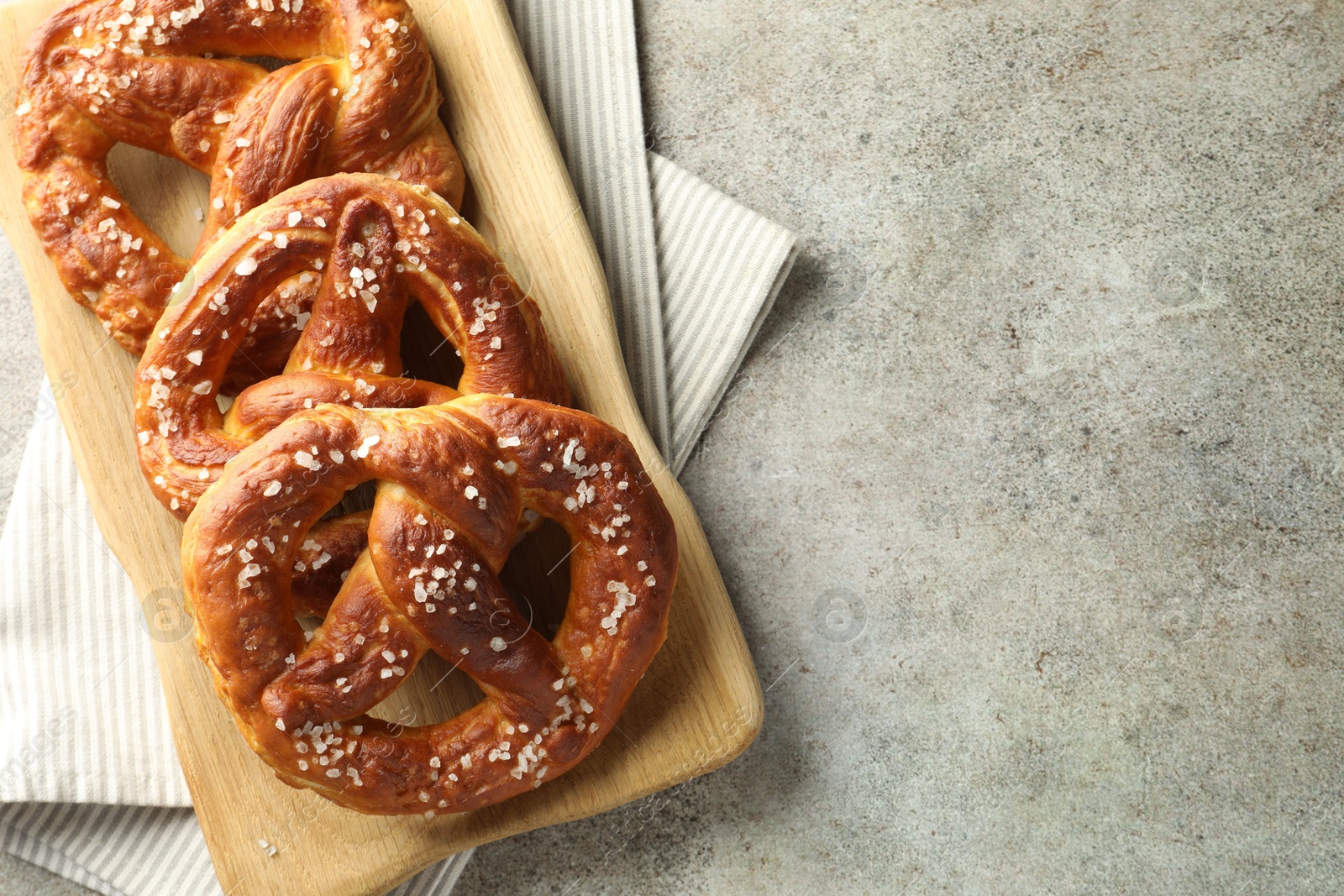 Tasty pretzels with salt on grey table, top view. Space for text Photo of Tasty pretzels with salt on grey table, top view. Space for text