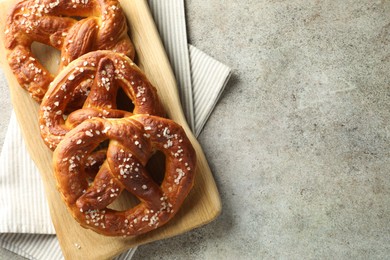 Photo of Tasty pretzels with salt on grey table, top view. Space for text