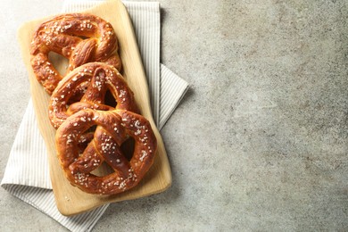 Photo of Tasty pretzels with salt on grey table, top view. Space for text