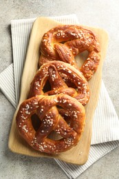 Photo of Tasty pretzels with salt on grey table, top view