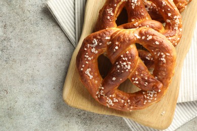 Photo of Tasty pretzels with salt on grey table, top view. Space for text