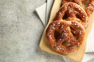 Photo of Tasty pretzels with salt on grey table, top view. Space for text
