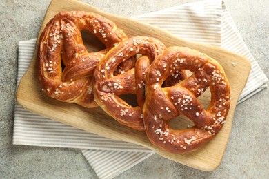 Photo of Tasty pretzels with salt on grey table, top view