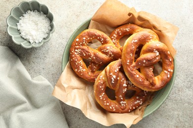 Photo of Tasty pretzels with salt on grey table, flat lay