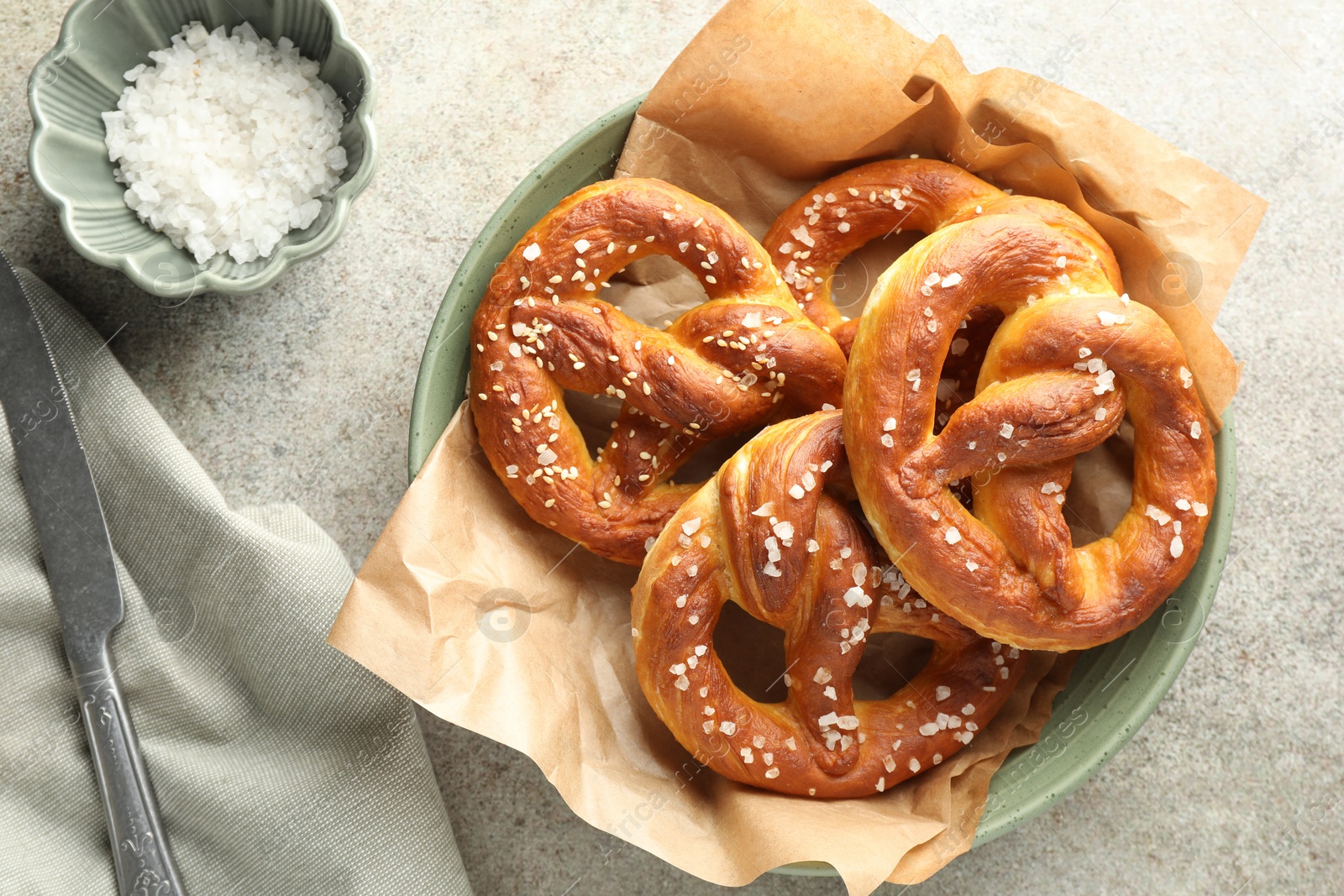 Tasty pretzels with salt on grey table, flat lay Photo of Tasty pretzels with salt on grey table, flat lay