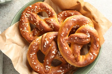Photo of Tasty pretzels with salt on grey table, top view