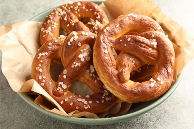Photo of Tasty pretzels with salt on grey table, closeup