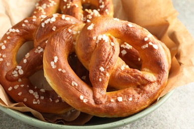 Photo of Tasty pretzels with salt on grey table, closeup