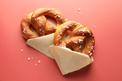 Photo of Tasty pretzels with salt on red background, flat lay