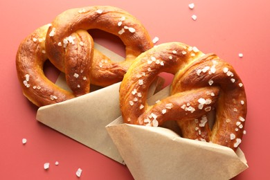 Photo of Tasty pretzels with salt on red background, flat lay