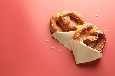 Photo of Tasty pretzels with salt on red background, flat lay. Space for text