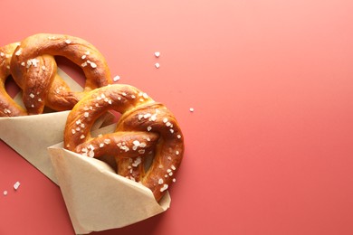 Photo of Tasty pretzels with salt on red background, flat lay. Space for text