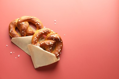 Photo of Tasty pretzels with salt on red background, flat lay. Space for text
