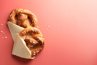 Photo of Tasty pretzels with salt on red background, flat lay. Space for text