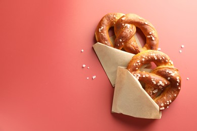 Photo of Tasty pretzels with salt on red background, flat lay. Space for text