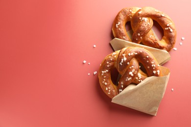 Photo of Tasty pretzels with salt on red background, flat lay. Space for text