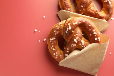 Photo of Tasty pretzels with salt on red background, flat lay. Space for text