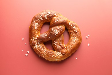 Photo of Tasty pretzel with salt on red background, top view