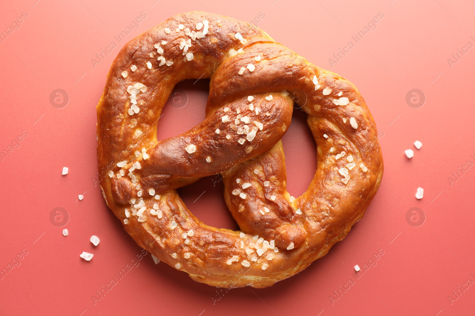 Tasty pretzel with salt on red background, top view Photo of Tasty pretzel with salt on red background, top view
