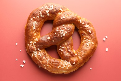 Photo of Tasty pretzel with salt on red background, top view