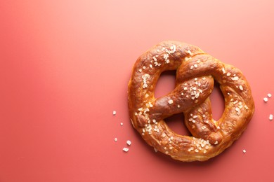 Photo of Tasty pretzel with salt on red background, top view. Space for text