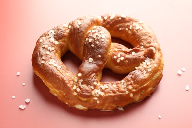 Photo of Tasty pretzel with salt on red background, closeup