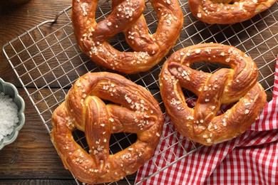 Photo of Tasty pretzels with salt on wooden table, flat lay