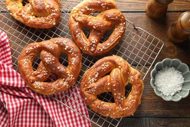 Photo of Tasty pretzels with salt on wooden table, flat lay